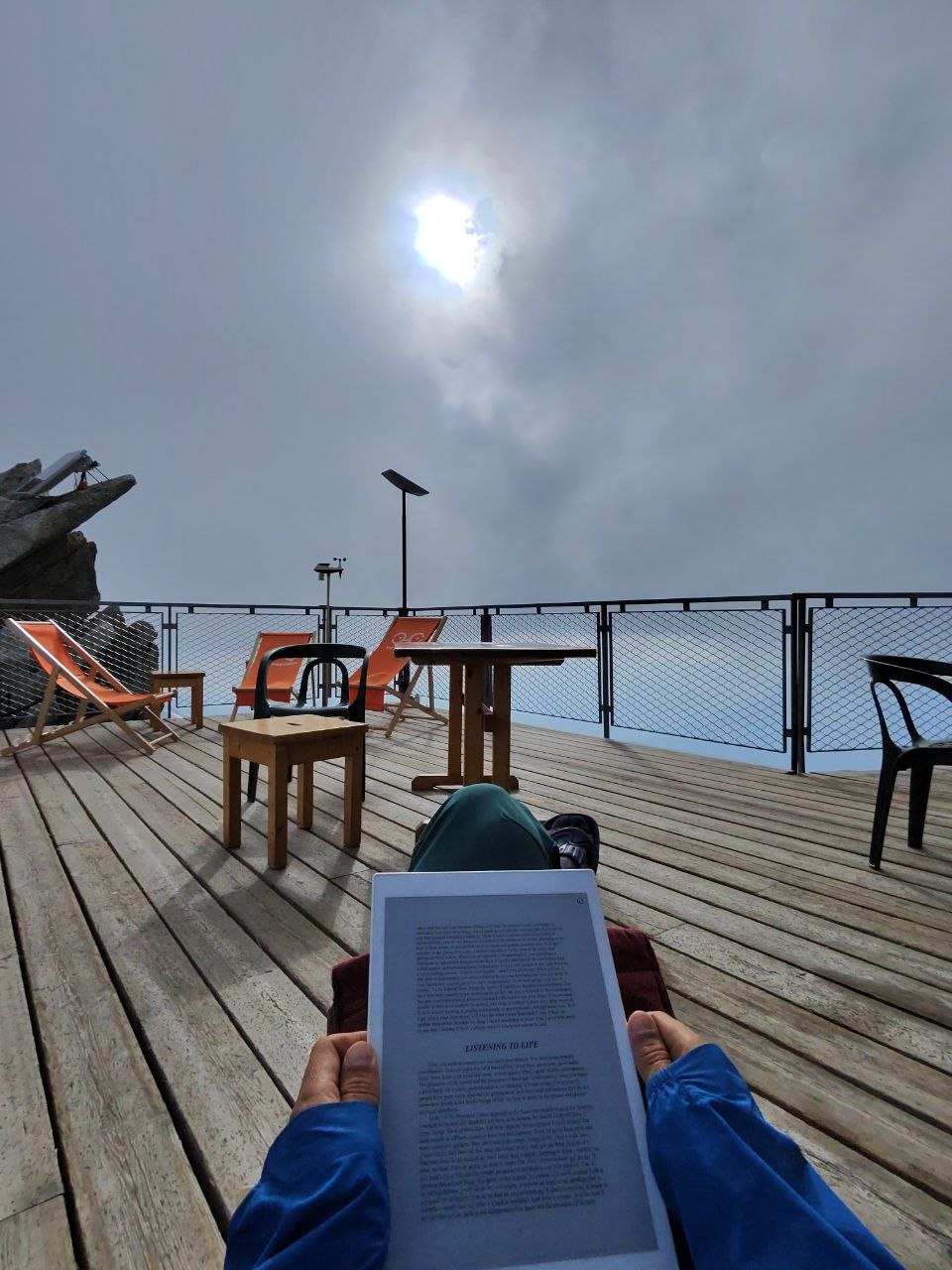 Reading on the reMarkable at Aiguille du Midi (3,842m), Mont Blanc — 'Listening to Life' on screen, wooden terrace above the clouds